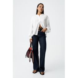 Blusa blanca de manga larga con rayas verticales y detalles brillantes. Botones frontales y puños elásticos.