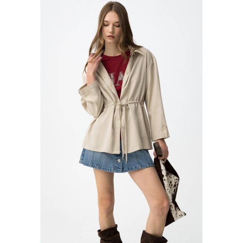 Camisa beige de corte relaxed, con cordón ajustable en la cintura y botones delanteros visibles.