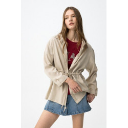 Camisa beige de corte relaxed, con cordón ajustable en la cintura y botones delanteros visibles.