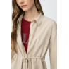 Camisa beige de corte relaxed, con cordón ajustable en la cintura y botones delanteros visibles.