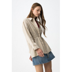 Camisa beige de corte relaxed, con cordón ajustable en la cintura y botones delanteros visibles.