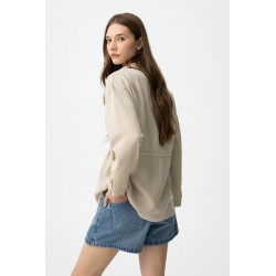 Camisa beige de corte relaxed, con cordón ajustable en la cintura y botones delanteros visibles.