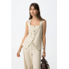 Top de color beige, corte ajustado, sin mangas, botones metálicos y dos bolsillos decorativos delante.