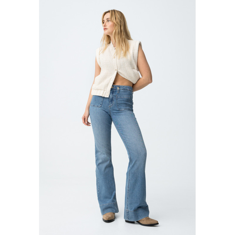 Vaqueros de corte flare en azul claro, con bolsillos delanteros y cierre de botón metálico.