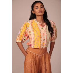 La prenda cuenta con un cuello fruncido con un pequeño volante que aporta un toque romántico y artesanal al escote. Su cierre fr