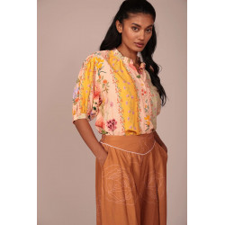 La prenda cuenta con un cuello fruncido con un pequeño volante que aporta un toque romántico y artesanal al escote. Su cierre fr