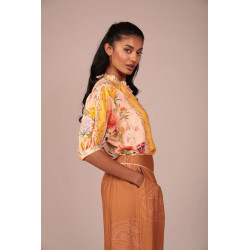 La prenda cuenta con un cuello fruncido con un pequeño volante que aporta un toque romántico y artesanal al escote. Su cierre fr