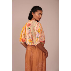 La prenda cuenta con un cuello fruncido con un pequeño volante que aporta un toque romántico y artesanal al escote. Su cierre fr