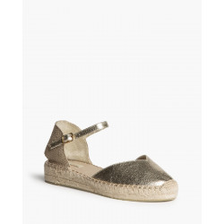 Alpargata de cuña baja, acabado dorado metalizado, caracterizada por su suela de yute trenzado y cierre de pulsera hebilla