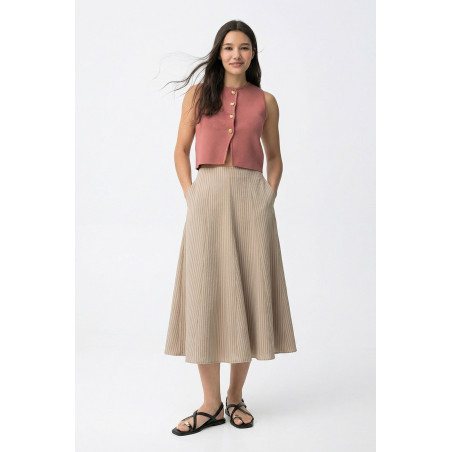 Falda de color beige, corte midi, caída amplia y pliegues finos en diseño relajado y casual.