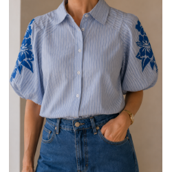 Camisa de botones a rayas verticales en color azul claro y blanco, caracterizada por sus mangas  abullonadas cortas con llamativ