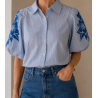 Camisa de botones a rayas verticales en color azul claro y blanco, caracterizada por sus mangas  abullonadas cortas con llamativ