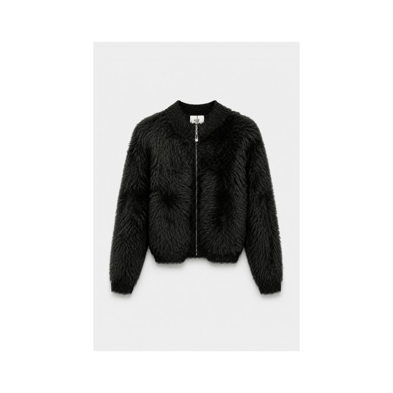 Chaqueta corta de tejido con textura de pelo largo. Cuello redondo y mangas largas de canalé. Ribetes de canalé y cierre de crem